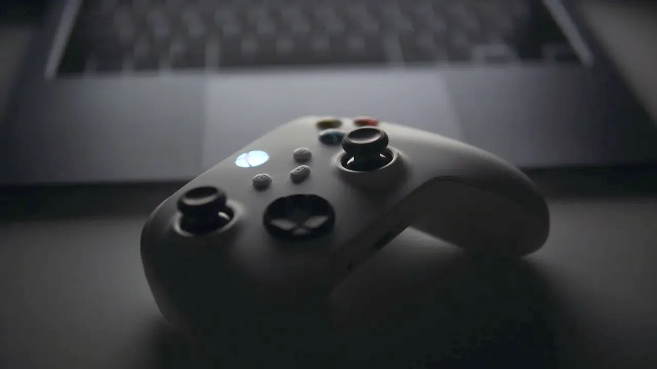 Un controller appoggiato davanti a un portatile in penombra
